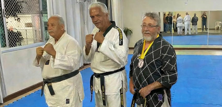 Três pessoas idosas praticando taekwondo
