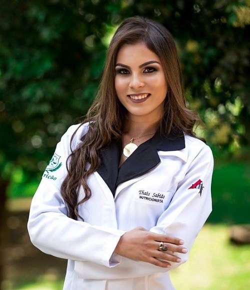 Foto da pesquisadora com os braços cruzados e jaleco da Nutrição da UFOP