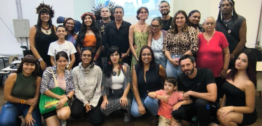 Grupo de pessoas de diferentes idades, incluindo algumas com acessórios de povos indígenas.