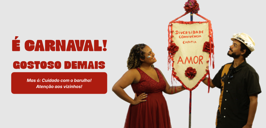 Duas pessoas seguram estandarte de Carnaval. 