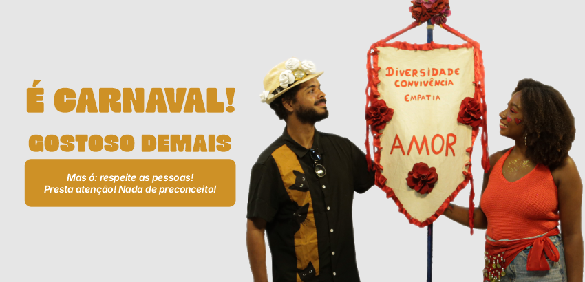 Duas pessoas seguram estandarte de Carnaval. 