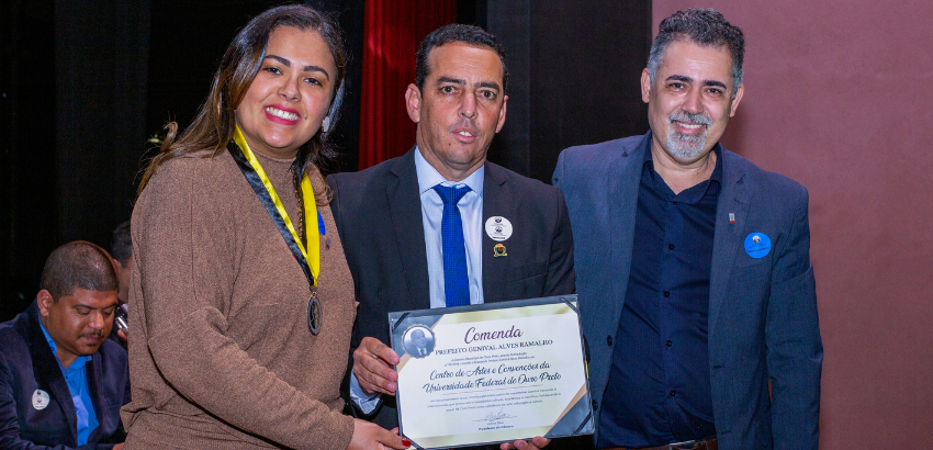 Três pessoas possam com certificado em mãos