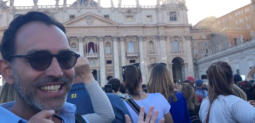  Homem sorrindo para câmera na frente de multidão de pessoas em frente à Basílica de São Pedro em Roma