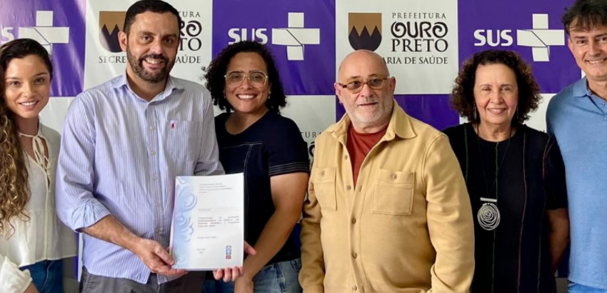 Homens e mulheres perfilados para a foto. Ao centro, pesquisadores seguram o resultado da pesquisa desenvolvida com à UFOP. 