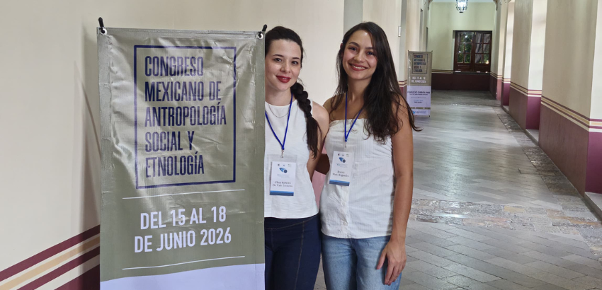 Alunos da pós-graduação posam ao lado do banner do evento