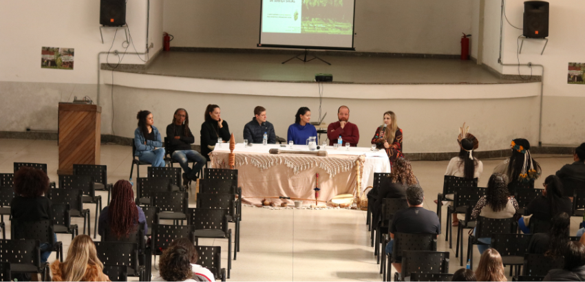 Pessoas assistem a mesa de debate durante o Fórum de Estágio em Serviço Social da UFOP, com painel projetado ao fundo e participação de lideranças e docentes.