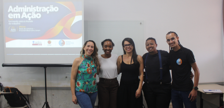 Cinco pessoas em pé ao lado da exibição de slides para palestra
