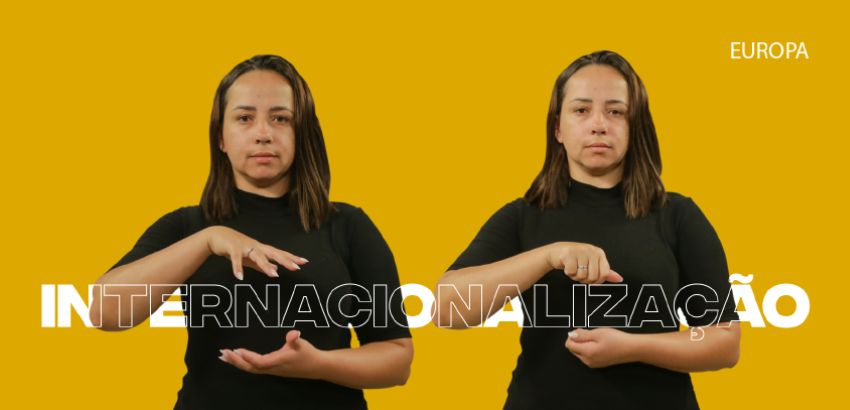 Duas mulheres fazem o sinal de "internacionalização" em Libras, lado a lado, sobre fundo amarelo. Ambas usam camiseta preta e expressão séria. A palavra "INTERNACIONALIZAÇÃO" aparece em branco com destaque, e "EUROPA" está no canto superior direito.