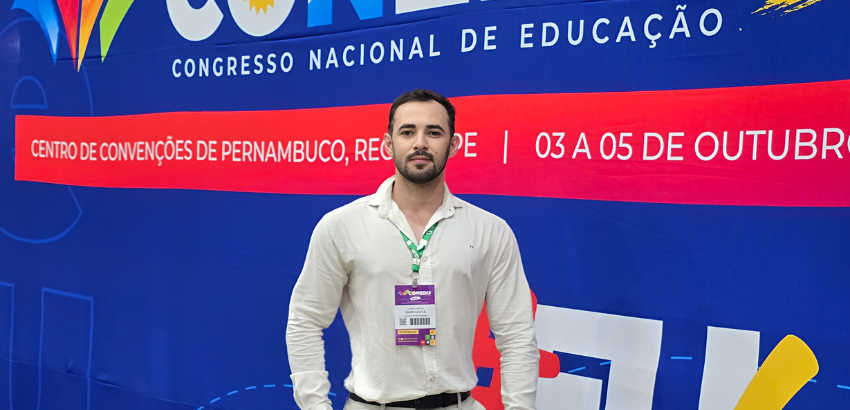 Homem em pé em frente a um painel do Congresso Nacional de Educação (CONEDU), realizado no Centro de Convenções de Pernambuco, Recife, entre os dias 03 a 05 de outubro.