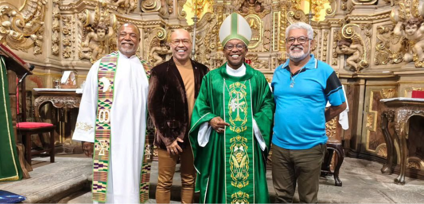 Mostra o bispo Dom Gabriel dos Santos Filho com vestes sacerdotais com os professores Erisvaldo dos Santos e Clézio Gonçalves da UFOP, no altar da Matriz de Santa Efigênia, em Ouro Preto. Eles estão reunidos para o V Encontro Nacional das Irmadades Negras