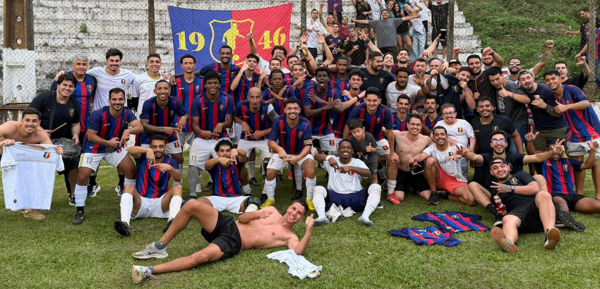 A imagem mostra um grande grupo de jogadores e torcedores reunidos em um campo de futebol, celebrando.