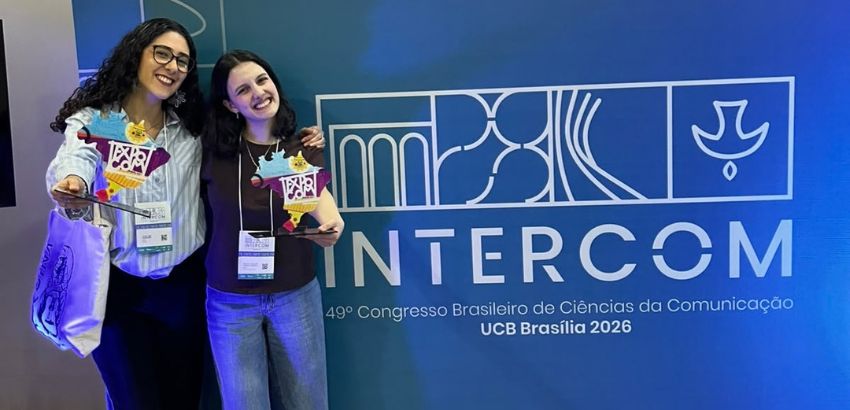 Duas mulheres sorrindo e segurando troféus durante o 49º Congresso Brasileiro de Ciências da Comunicação, em Brasília.
