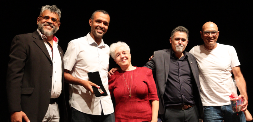 A foto mostra a família de Sílvia com o reitor e o chefe de gabinete, posando para a foto.