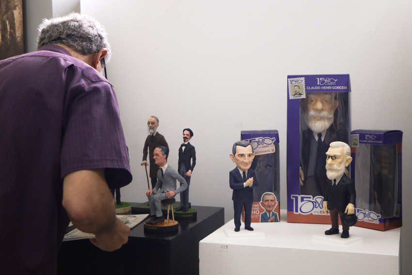 Visitante observa miniaturas e bonecos colecionáveis de Claude-Henri Gorceix e de outras figuras históricas, expostos em uma mostra comemorativa dos 150 anos da Escola de Minas de Ouro Preto.