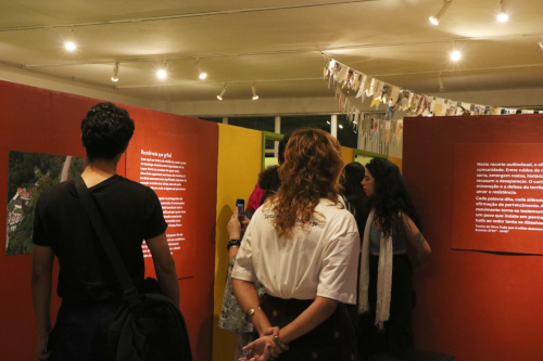 Visitantes circulam pela exposição, observando painéis e conteúdos da exposição realizada pelo curso de museologia da UFOP.