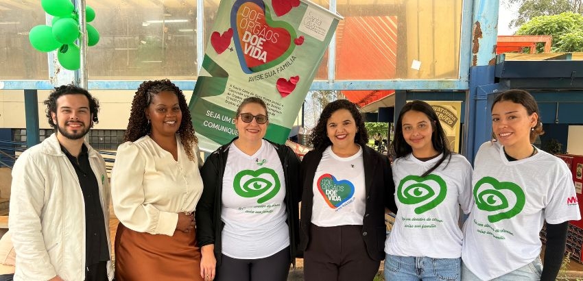 Foto da Vice-Reitora, Profª Iara, servidora Lisiane e bolsistas em pé, sorrindo. Quatro deles vestem a camisa da campanha Doe Órgãos, Doe Vida.