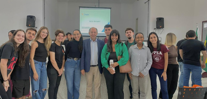 Grupo de estudantes e professores sorrindo em sala de aula após apresentação.