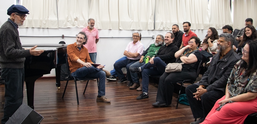 Durante a homenagem no curso de Música da UFOP, Rufo Herrera fala ao público com leveza e emoção. Sentado em roda, o grupo de professores, alunos e amigos ouve atentamente, entre risos e expressões de carinho.