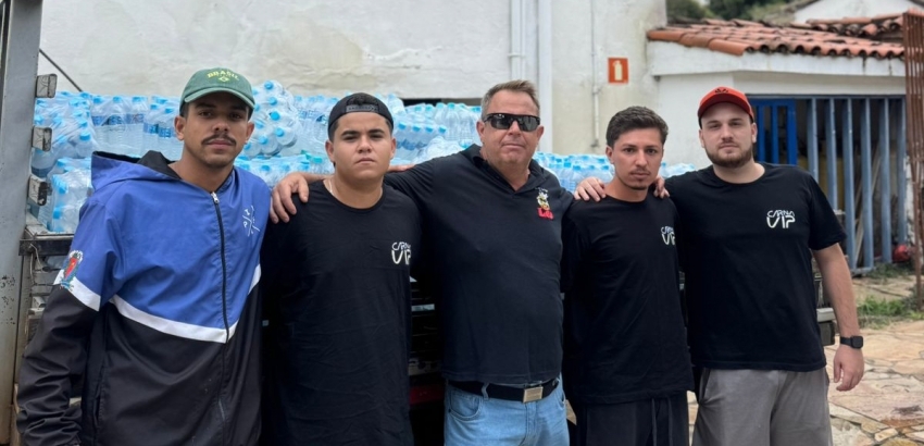 Doação de repúblicas para Ubá A foto mostra um grupo de homens na frente de um caminhão carregado de fardos de água.