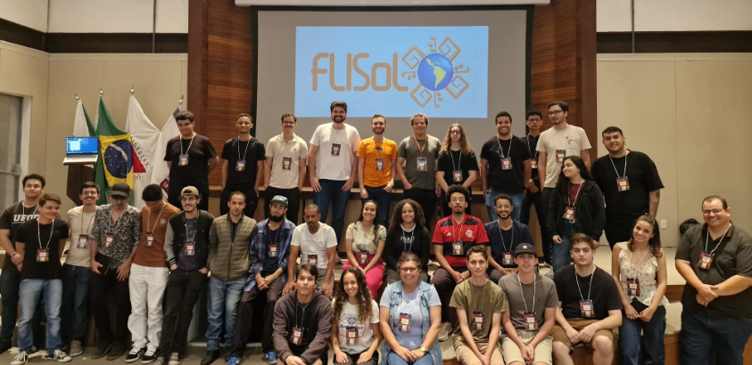 Foto em grupo dos participantes da primeira edição do Festival Latino-Americano de Instalação de Software Livre no auditório do ICEA/UFOP, em João Monlevade. Estudantes, professores e organizadores, posam em frente ao palco abai