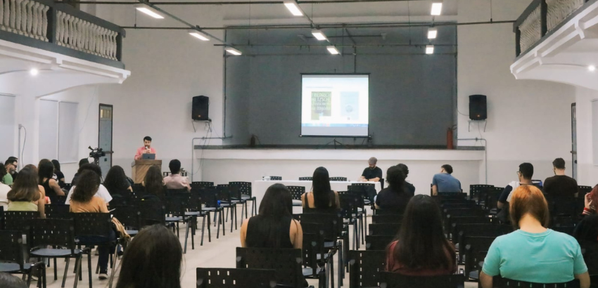 Pessoas sentadas em um auditório escutando palestra do professor Eli Borges