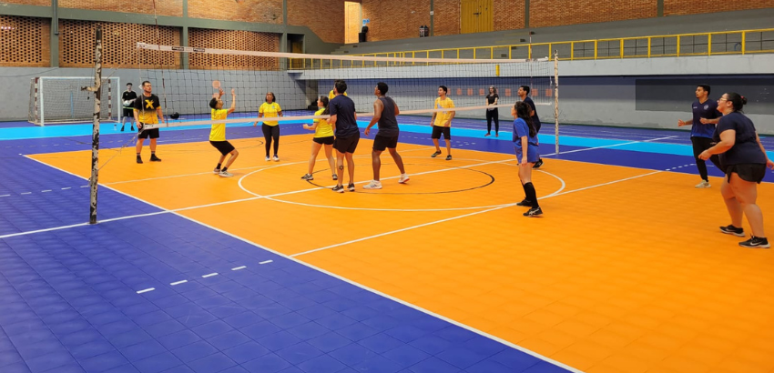 Grupo de pessoas jogando voleibol na quadra do ginásio poliesportivo