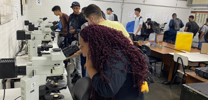 Foto dos estudantes olhando microscópios no DEGEO