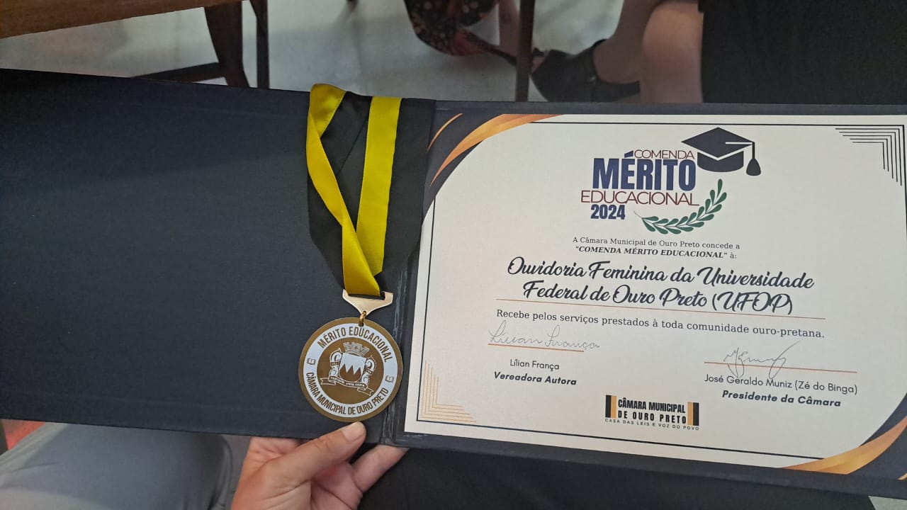 Medalha e certificado da Comenda de Mérito Educacional concedido à Ouvidoria Feminina da UFOP.