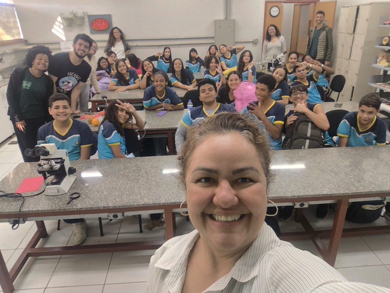 alunos e professores reunidos no laboratório de biologia durante a visita.